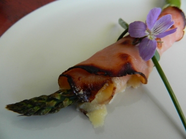 A little practise run for someone's sixty-fifth: asparagus wrapped with gouda cheese and ham, all tied up with a chive and a violet blossom. Before dressing with chives and violets, broil asparagus until ham and cheese is golden.